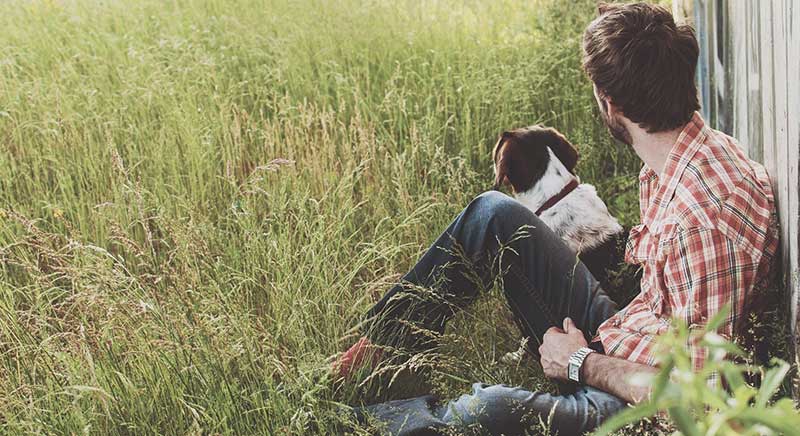 man and dog sitting in a grassy field